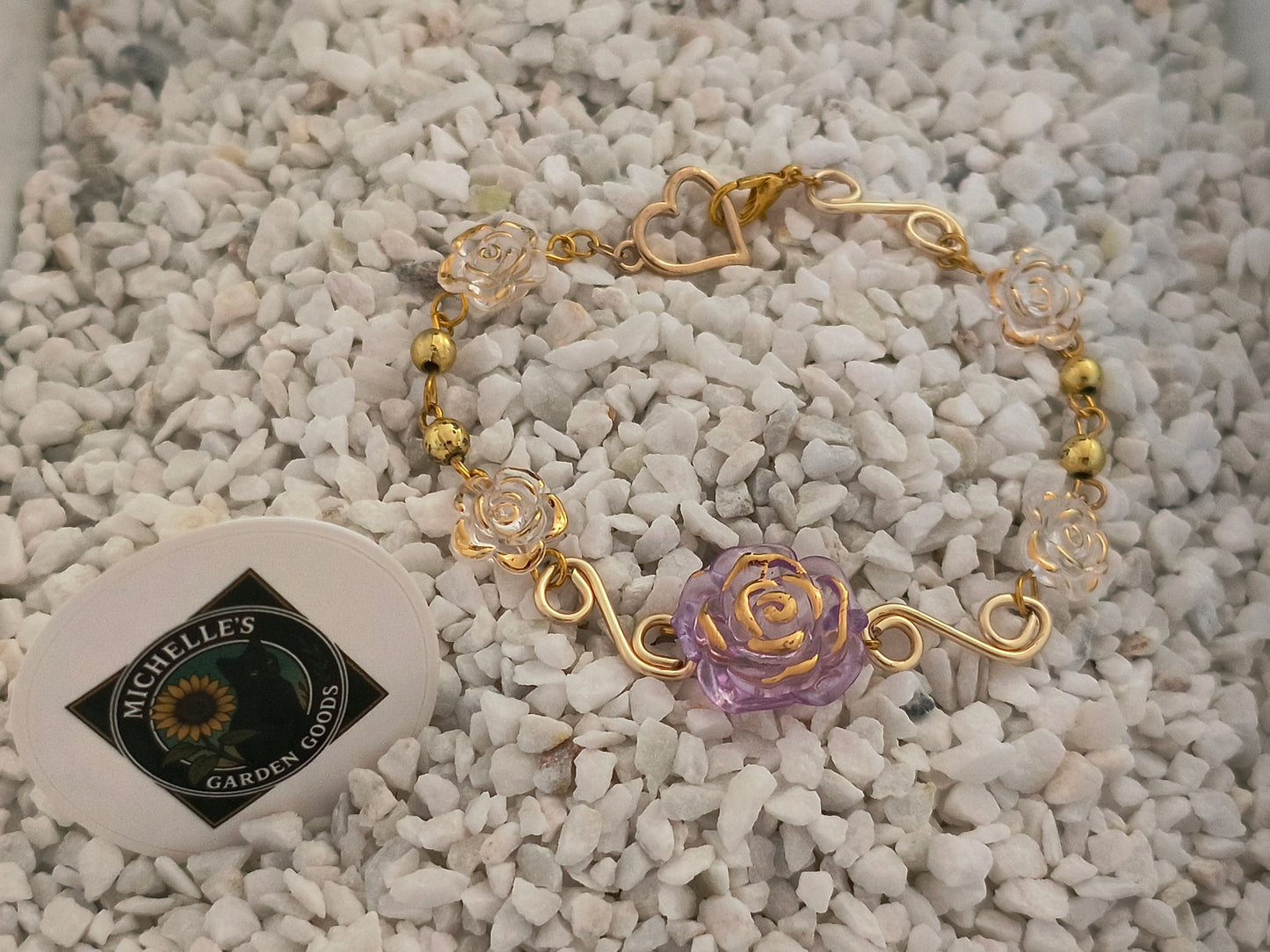 Spiral Wire Rose Bracelet With Gold Heart Clasp
This Handmade Bracelet has Gold Spiral Wire Between White and Light Purple Flowers. Gold Beads and a Cute Gold Heart Shaped Clasp.
Dimensions H 7" x L 1" x W 0.375". Weight 0.24 Oz.