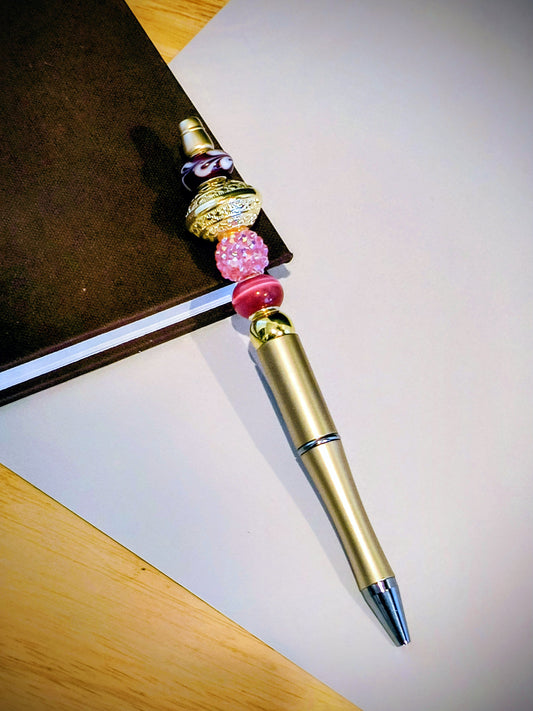 Be the talk of the office with these wonderful colorful fun pens. Each pen comes with extra ink cartridge. This is a Sparking Pink and Gold Beaded decor on a Gold Pen. 
Dimensions 5.75" x .5" x .75". Weight .58 Oz.
