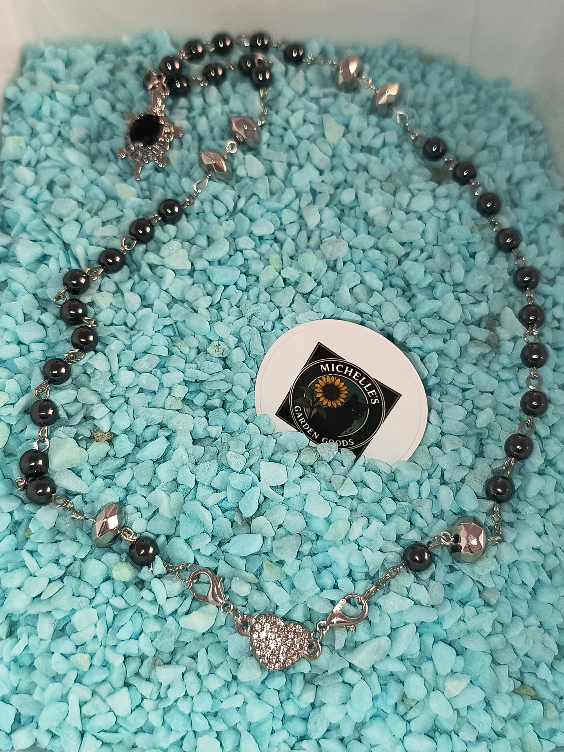This Handmade Hematite Necklace With A Sapphire Turtle Charm. Held together by a Rhinestone Magnetic Heart

2 In 1 Design using the Heart Clasp or the Turtle Charm

Dimensions H 11" x L 0.625" x W 0.5". Weight 1.04 Oz.
